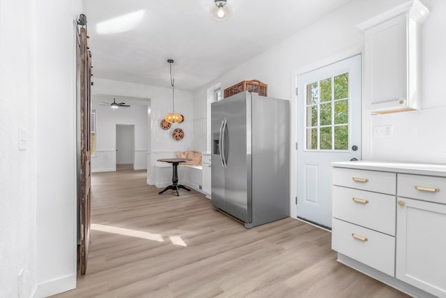 kitchen with light hardwood / wood-style floors, stainless steel fridge with ice dispenser, hanging light fixtures, and white cabinets