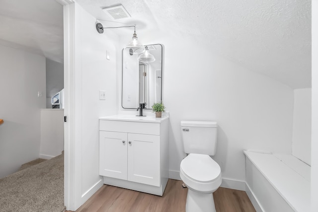 bathroom with vanity, toilet, hardwood / wood-style floors, and a textured ceiling