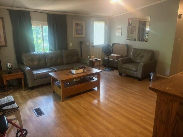 living room with ornamental molding and light hardwood / wood-style floors