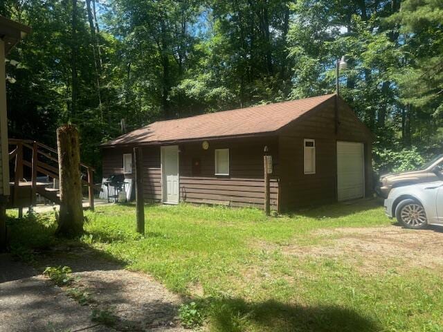 view of property exterior featuring a garage, a yard, and an outdoor structure