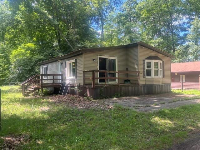 rear view of house featuring a wooden deck and a yard