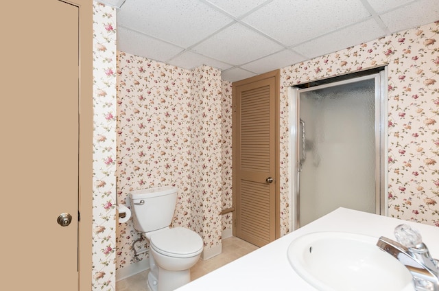 bathroom featuring vanity, a drop ceiling, tile patterned floors, and toilet