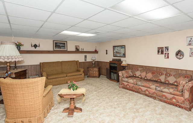 carpeted living room with a drop ceiling and wooden walls