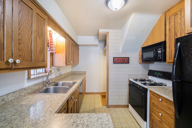 kitchen with sink, black appliances, and wood walls