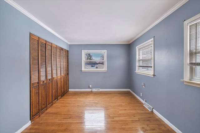 unfurnished bedroom featuring multiple windows, crown molding, and light wood-type flooring