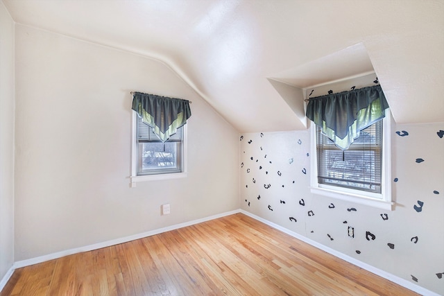 additional living space with a wealth of natural light, lofted ceiling, and hardwood / wood-style floors