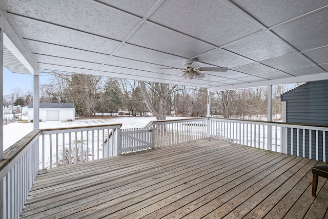 snow covered deck with ceiling fan and a storage shed