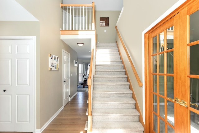 stairway with hardwood / wood-style floors and french doors