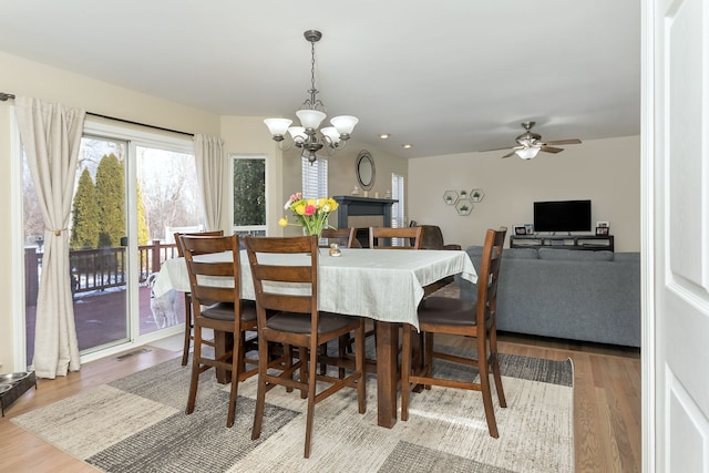 dining room with ceiling fan with notable chandelier and light hardwood / wood-style floors