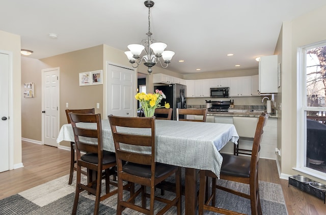 dining space featuring an inviting chandelier, sink, and wood-type flooring