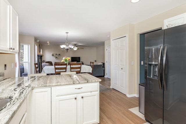 kitchen with white cabinetry, light stone countertops, stainless steel fridge, and light hardwood / wood-style floors