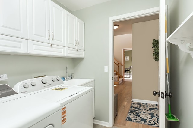 clothes washing area with cabinets, separate washer and dryer, sink, and light wood-type flooring