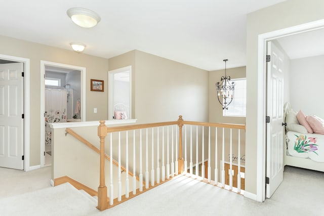 hallway with an inviting chandelier and carpet floors