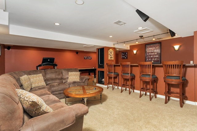 carpeted living room featuring indoor bar and rail lighting