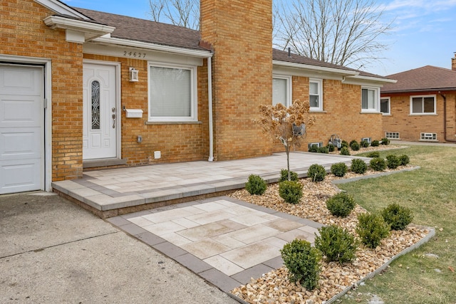 doorway to property with a yard, a patio, and a garage