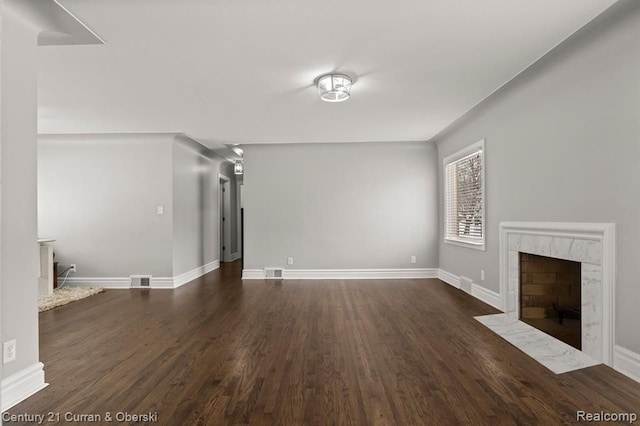 unfurnished living room with dark wood-type flooring and a high end fireplace