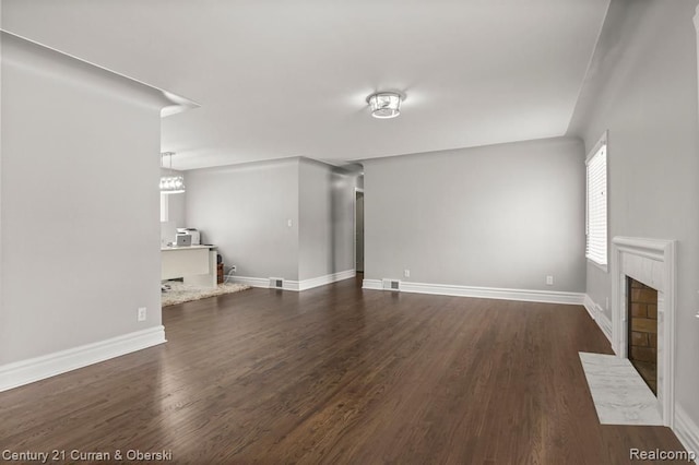 unfurnished living room with dark hardwood / wood-style flooring and a tiled fireplace