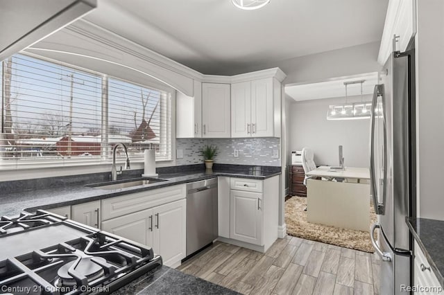 kitchen featuring stainless steel appliances, white cabinetry, hanging light fixtures, and sink