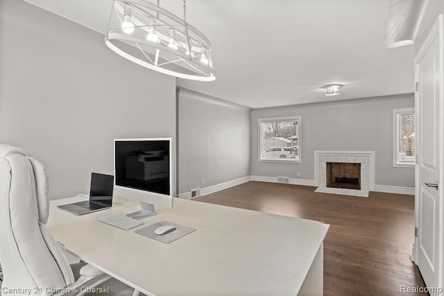 office space with dark hardwood / wood-style flooring, a high end fireplace, and a chandelier