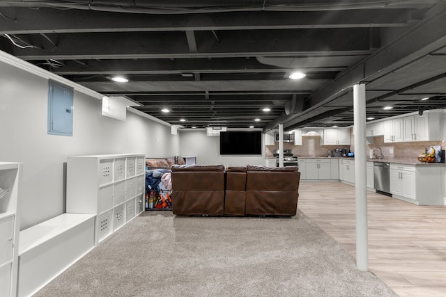 basement featuring sink, electric panel, and light hardwood / wood-style flooring