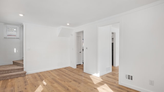 spare room featuring stairs, light wood finished floors, visible vents, and baseboards