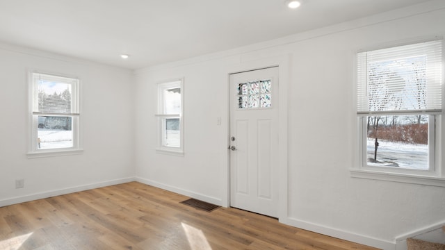 entryway featuring a healthy amount of sunlight, visible vents, baseboards, and wood finished floors