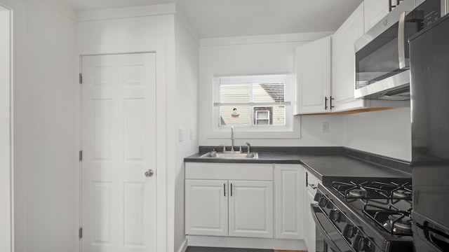 kitchen with refrigerator, dark countertops, stainless steel microwave, gas stove, and a sink