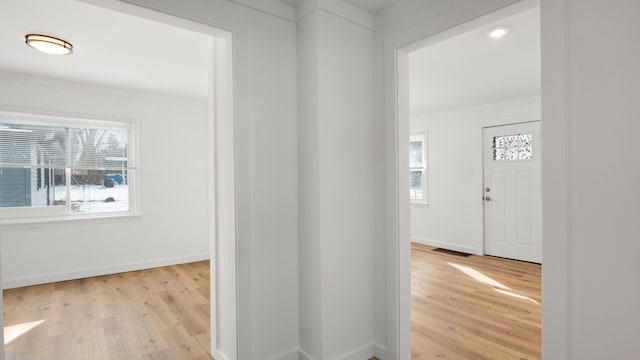 hall with visible vents, crown molding, light wood-style flooring, and baseboards