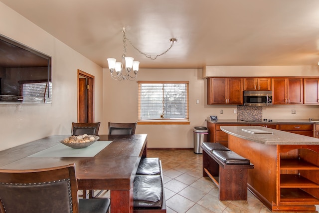 kitchen featuring light tile patterned floors, a breakfast bar area, a center island, a notable chandelier, and decorative light fixtures