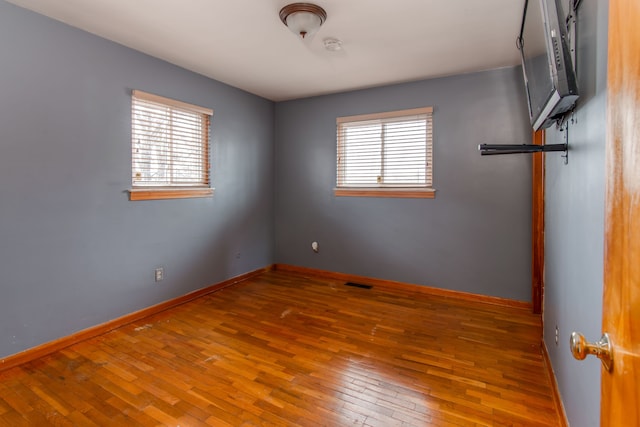 unfurnished room with hardwood / wood-style floors and plenty of natural light