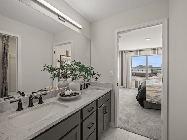 ensuite bathroom featuring a sink, ensuite bathroom, marble finish floor, and double vanity