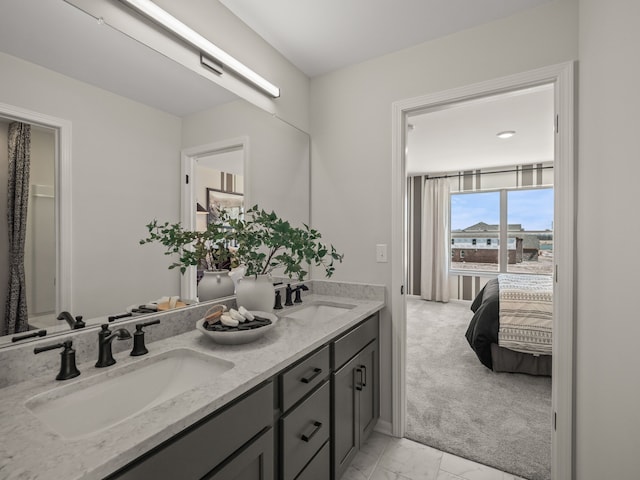 ensuite bathroom with a sink, baseboards, double vanity, and marble finish floor