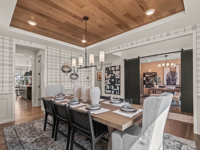 dining room featuring a barn door, wood finished floors, wood ceiling, and a tray ceiling