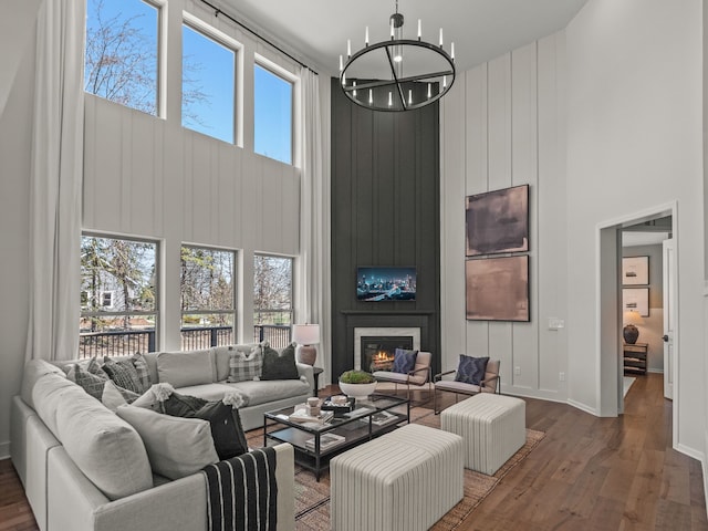 living area featuring a high ceiling, a fireplace, wood finished floors, and a chandelier