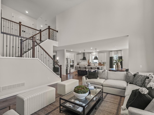 living area with visible vents, dark wood-style floors, recessed lighting, a high ceiling, and stairs