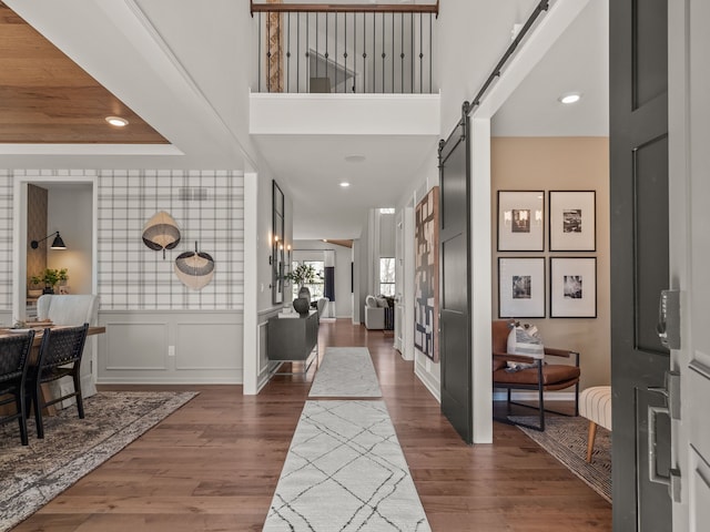 foyer entrance featuring a barn door, dark hardwood / wood-style floors, and a towering ceiling