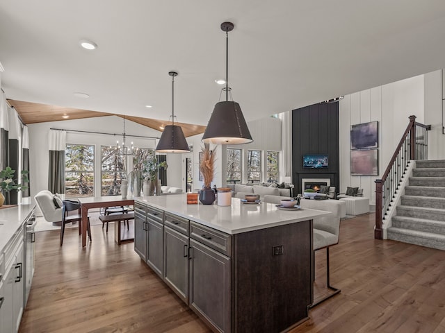 kitchen with light countertops, a kitchen breakfast bar, vaulted ceiling, and dark brown cabinets