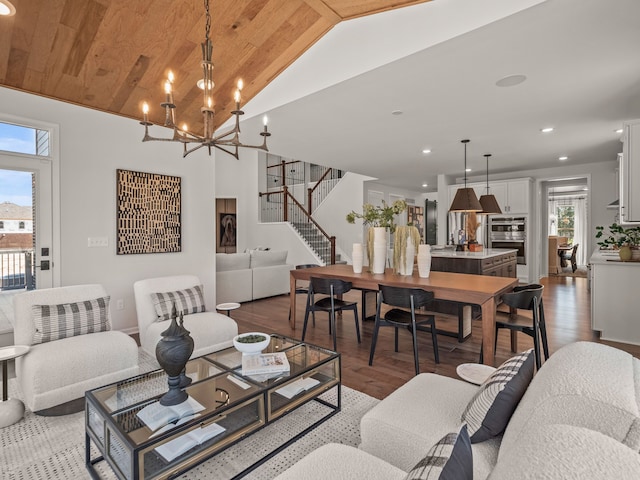 living room with a notable chandelier, recessed lighting, wood finished floors, vaulted ceiling, and stairway