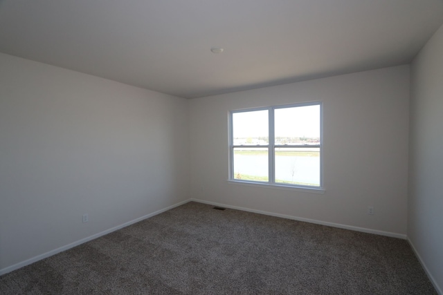 carpeted empty room featuring baseboards and visible vents