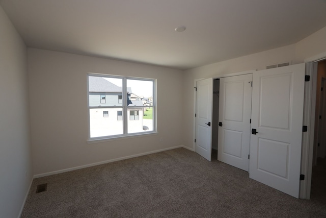 unfurnished bedroom with carpet floors, baseboards, and visible vents