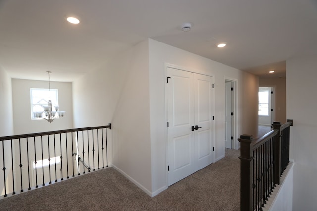 hallway with a notable chandelier, carpet floors, baseboards, an upstairs landing, and recessed lighting