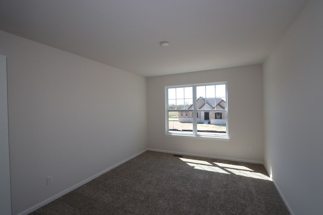 carpeted empty room featuring baseboards
