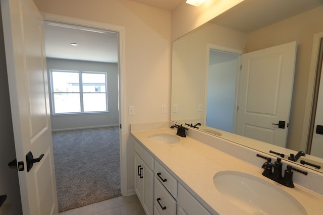 bathroom featuring a sink, baseboards, tile patterned flooring, and double vanity
