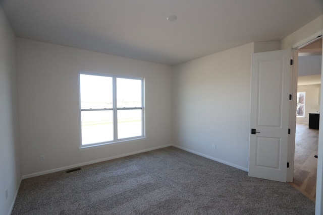 carpeted spare room with baseboards and visible vents