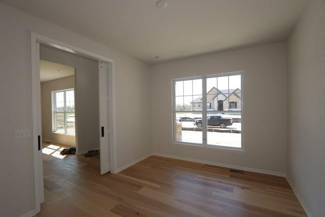 spare room featuring baseboards and light wood finished floors