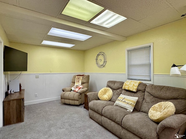 living room with a drop ceiling and carpet