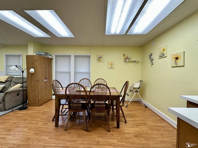 dining room featuring a paneled ceiling and light hardwood / wood-style flooring