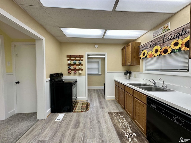 kitchen featuring a drop ceiling, sink, black appliances, and light wood-type flooring