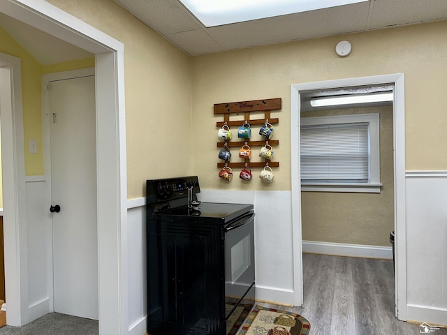 kitchen featuring black range with electric stovetop, hardwood / wood-style flooring, and a paneled ceiling