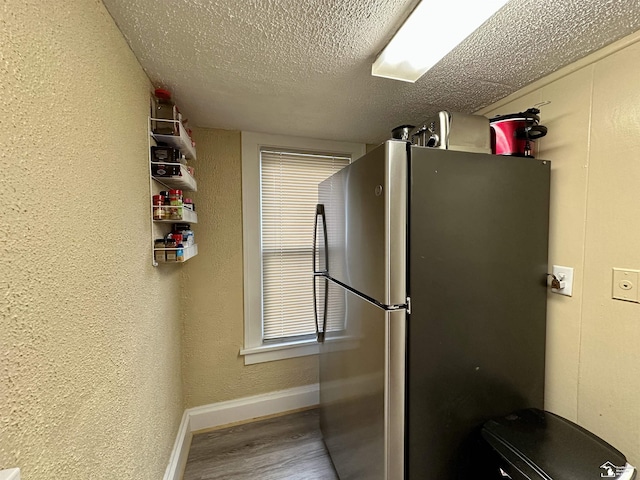 kitchen with wood-type flooring, stainless steel fridge, and a textured ceiling